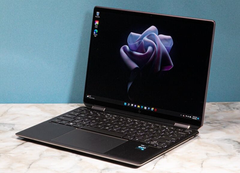 HP Spectre x360 laptop shown open at a front angle with dark chassis and OLED touchscreen display